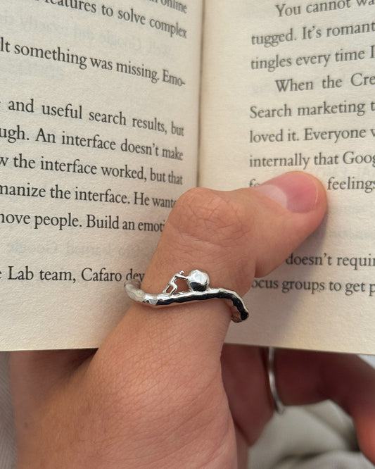 Sisyphus Ring worn on thumb while reading a book