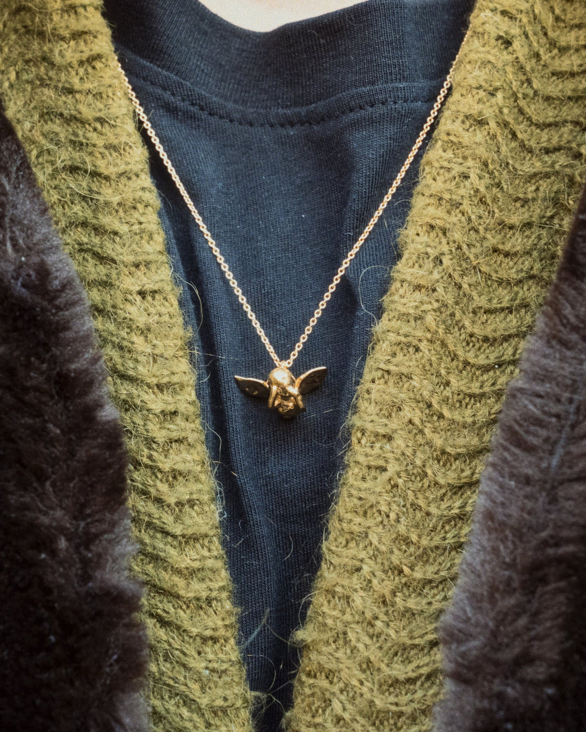 Cupid Necklace in gold worn with tshirt and green jacket