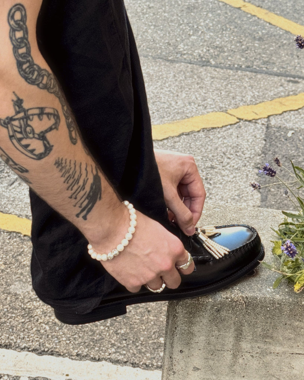 pearl tassel penny pins being worn on penny loafer with hand and tattoos visible