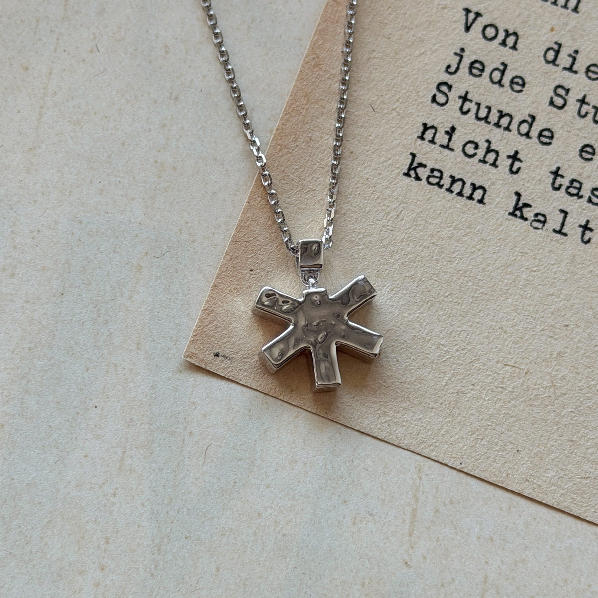 Self-Portrait Necklace in silver laid down on a book