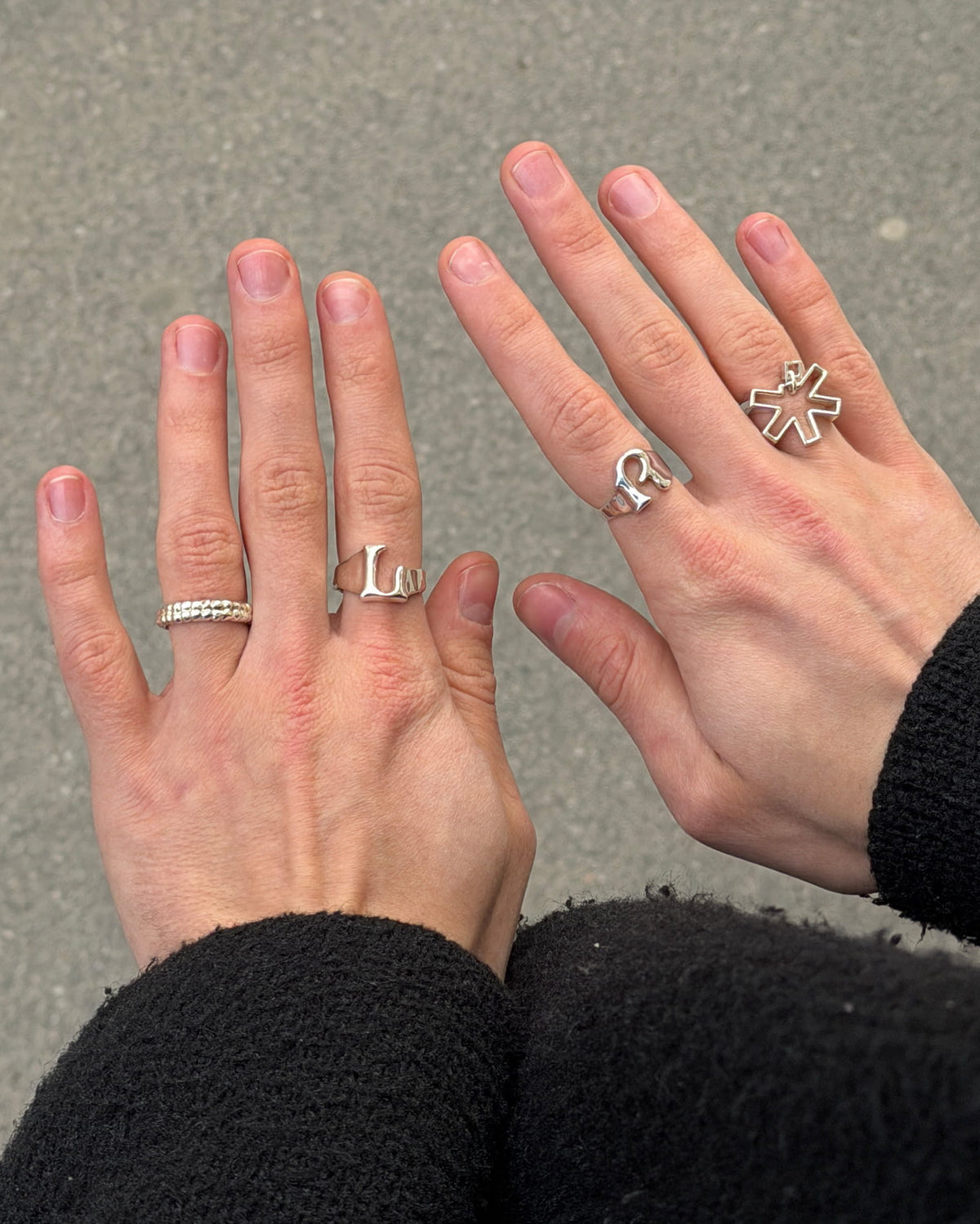 POV photo of hands with multiple silver rings including the Self Portrait ring