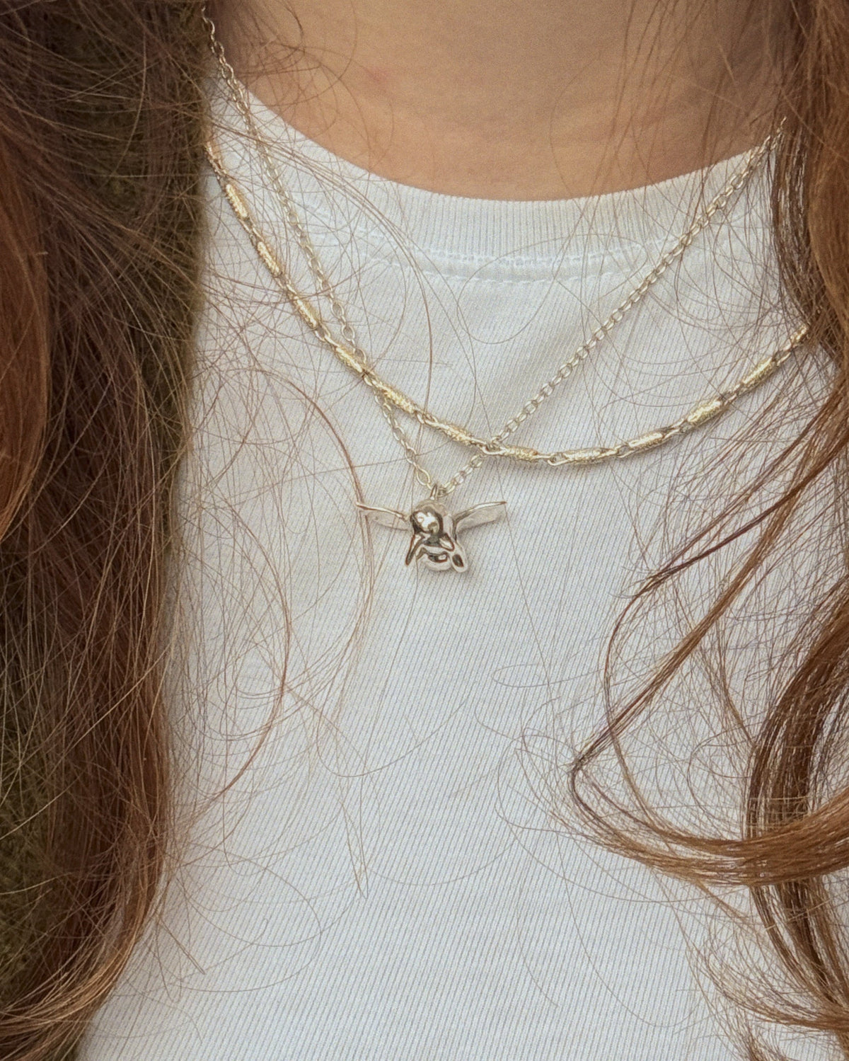 Pen Necklace worn on tshirt with Cupid Necklace by female