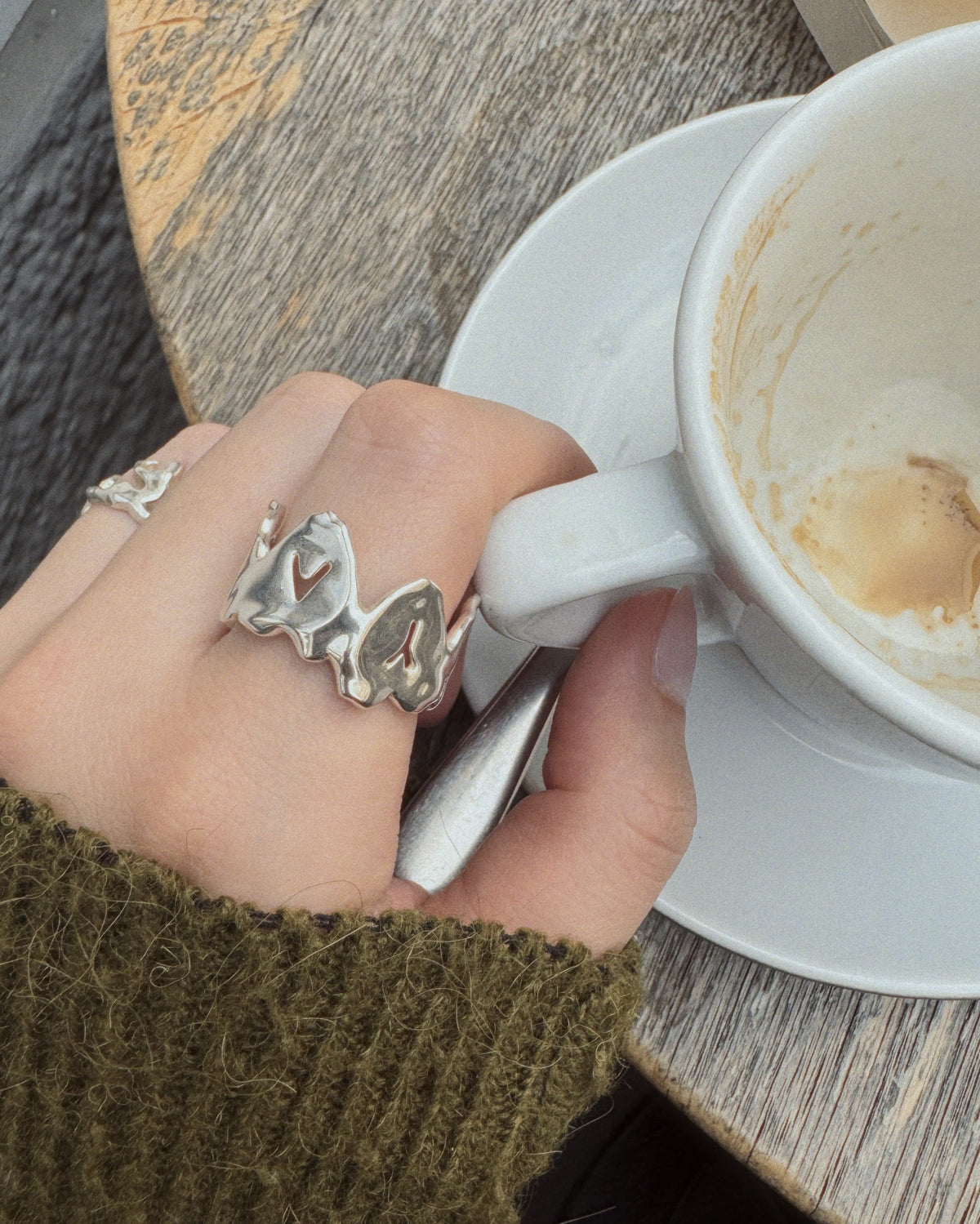 love ya ring in silver next to a empty cup of coffee