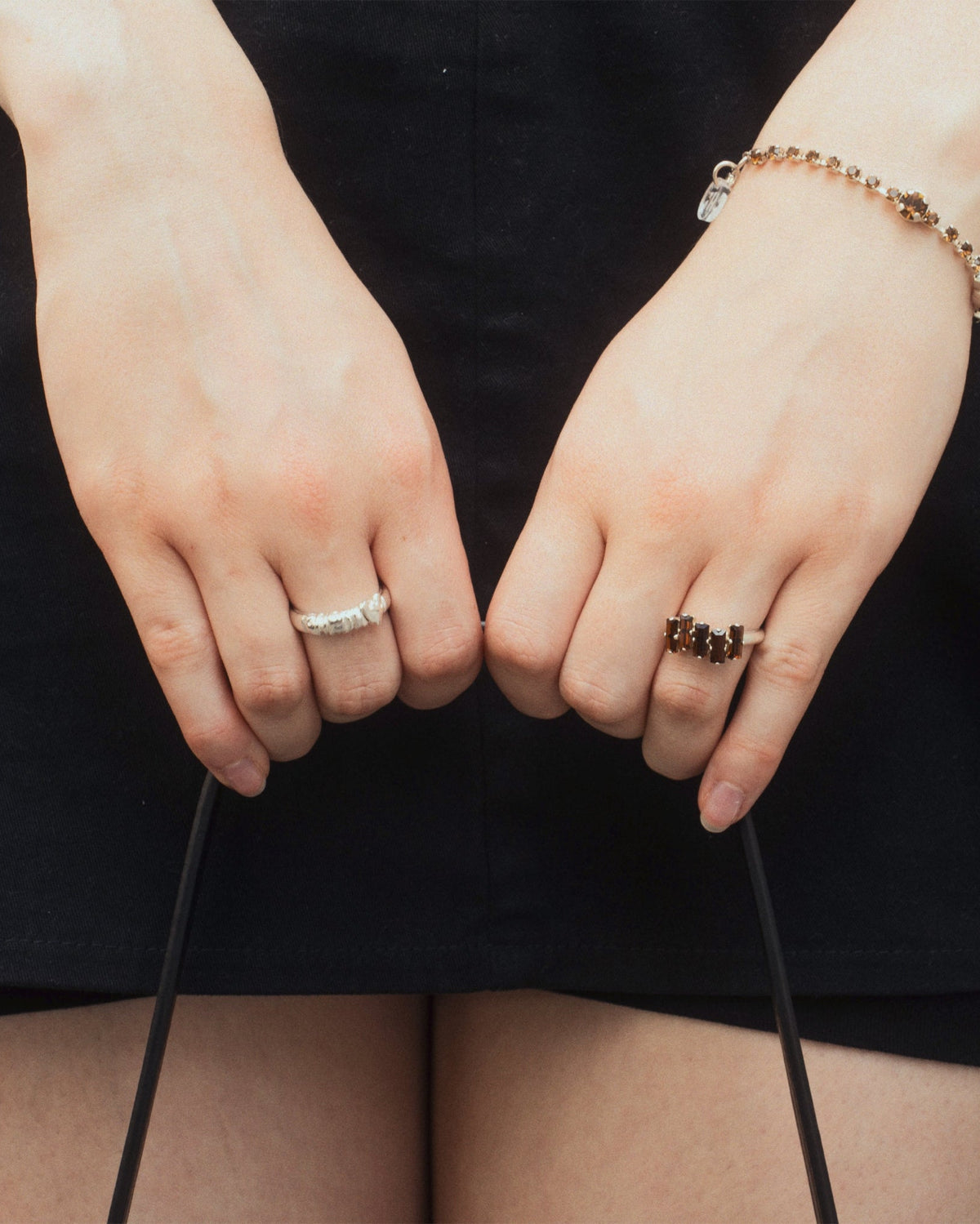 F*ck Off Ring worn on hand and holding a purse