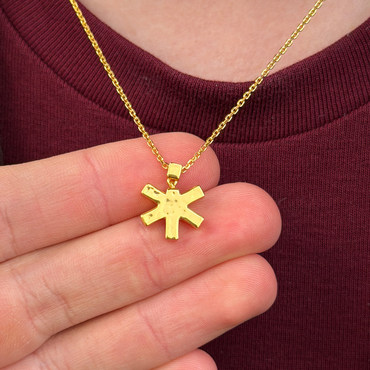 Self-Portrait Necklace holding pendant in hand while being worn in gold by female